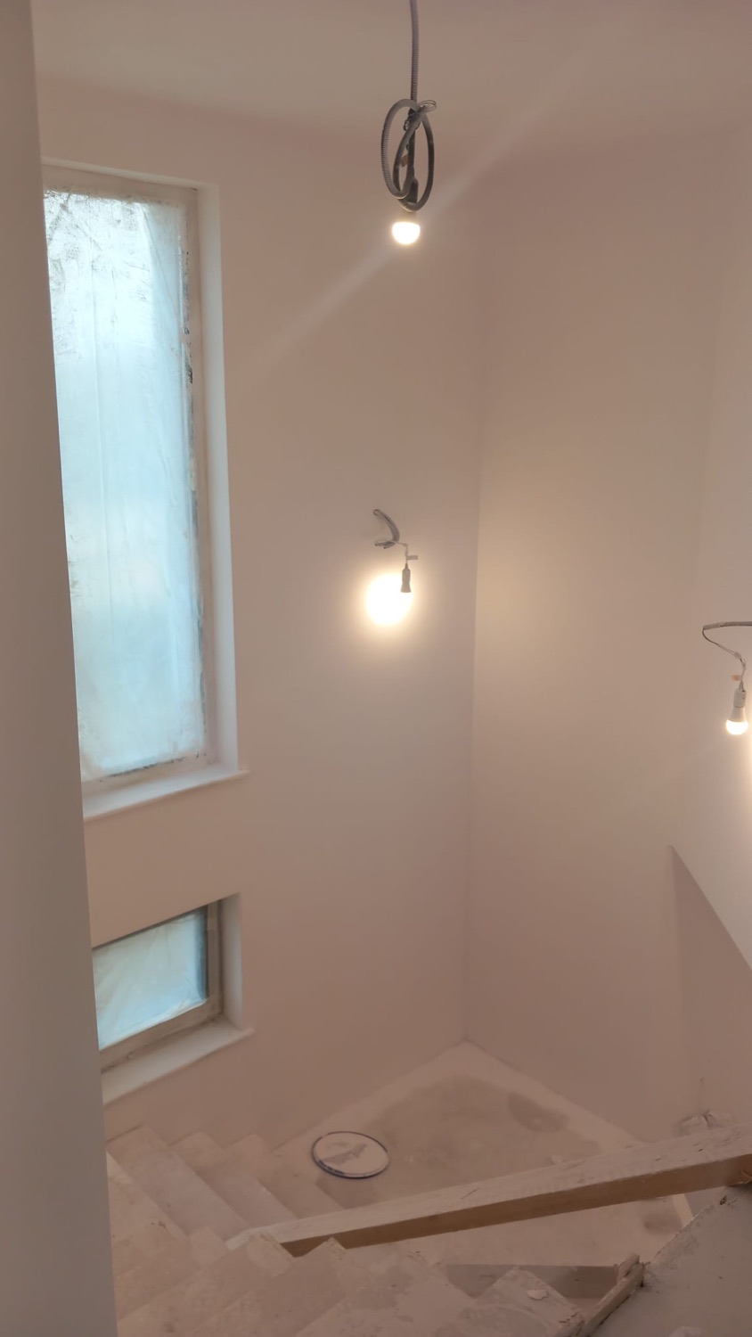 Casa scării zugrăvită în alb, cu ferestre înalte și corpuri de iluminat montate