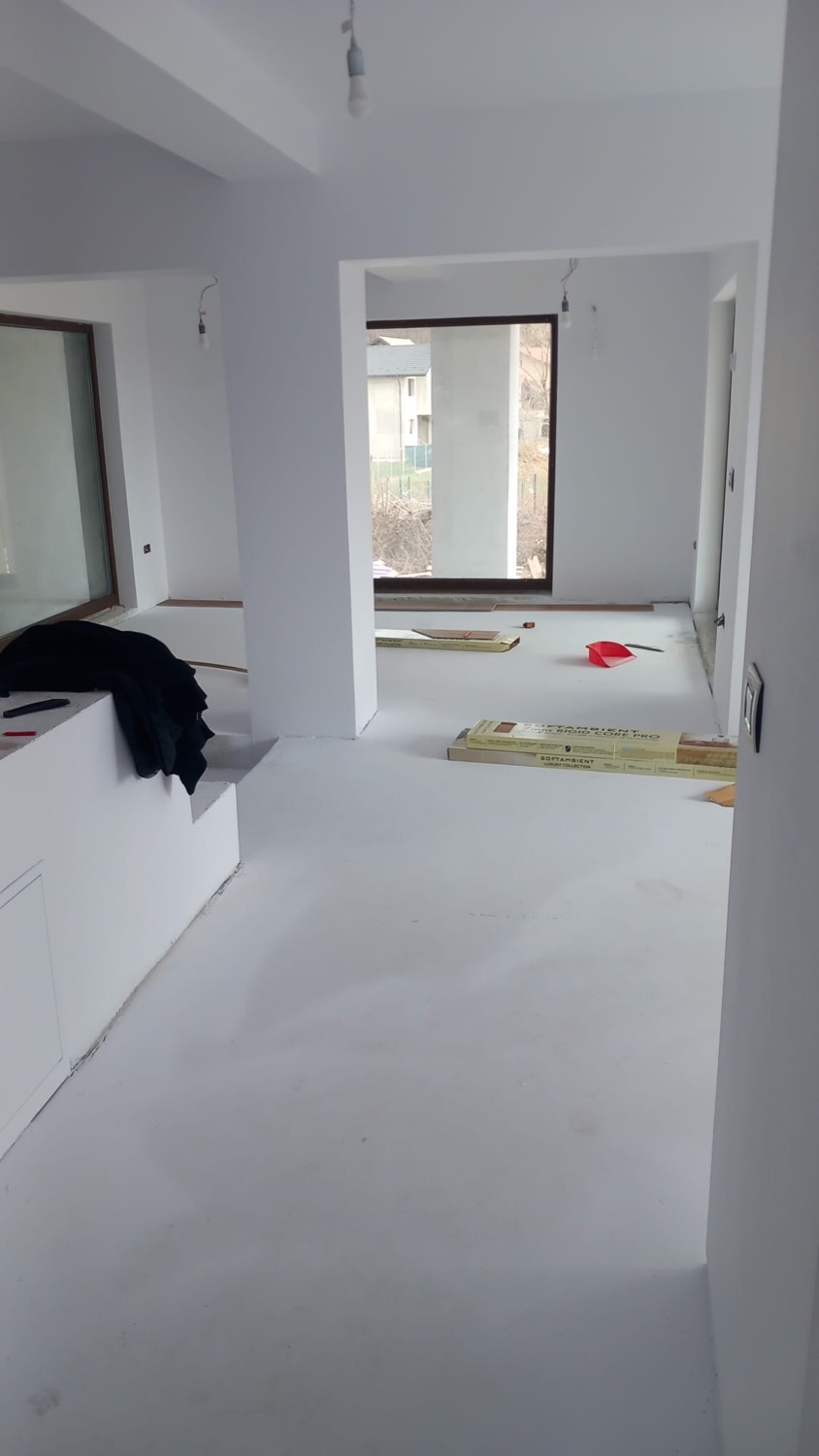 Living deschis, cu pereți finisați în alb și șapă autonivelantă turnată