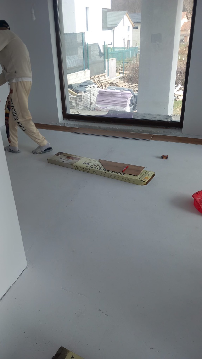 Meseriaș pregătind montajul parchetului laminat într-o cameră finisată