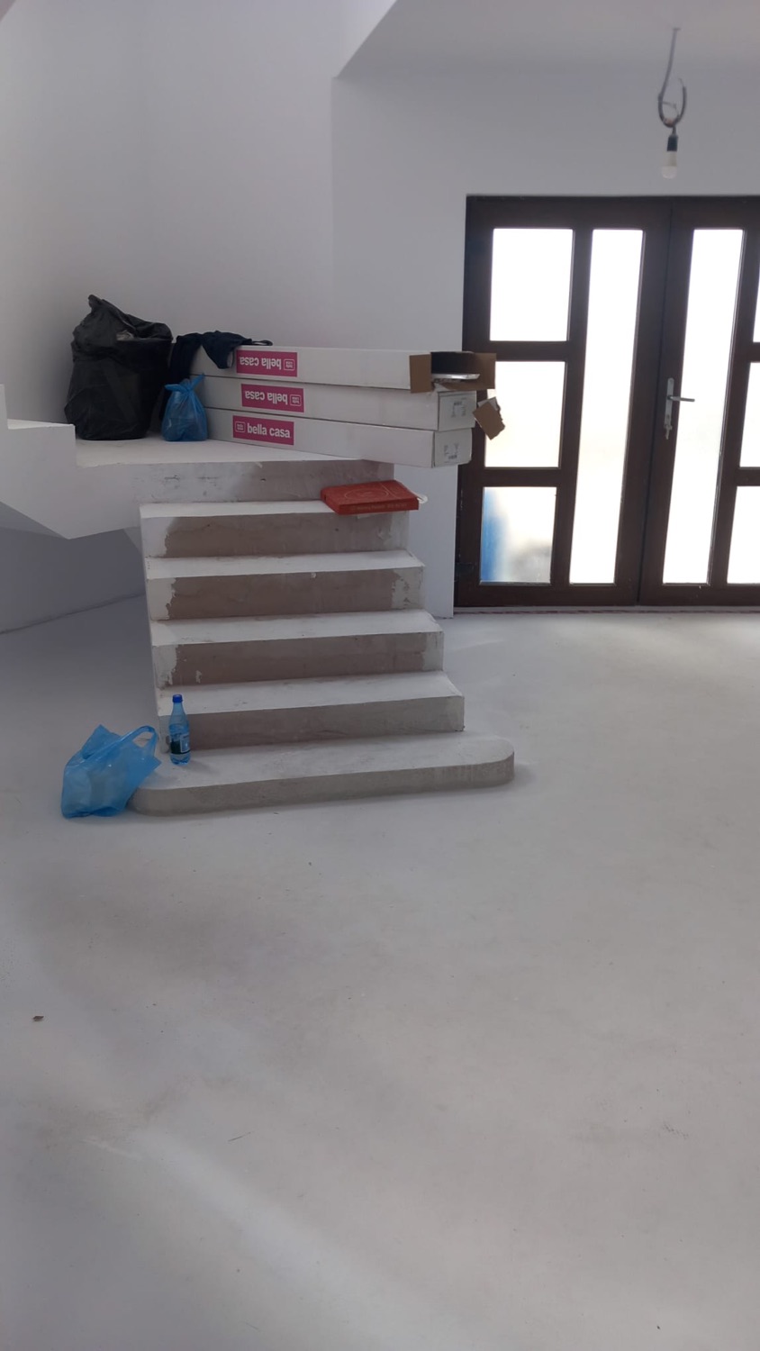 Scară interioară din beton finisată, într-un hol cu ușă de intrare din lemn